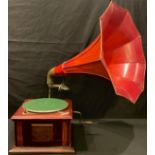 A table top gramophone with red trumpet horn, winder