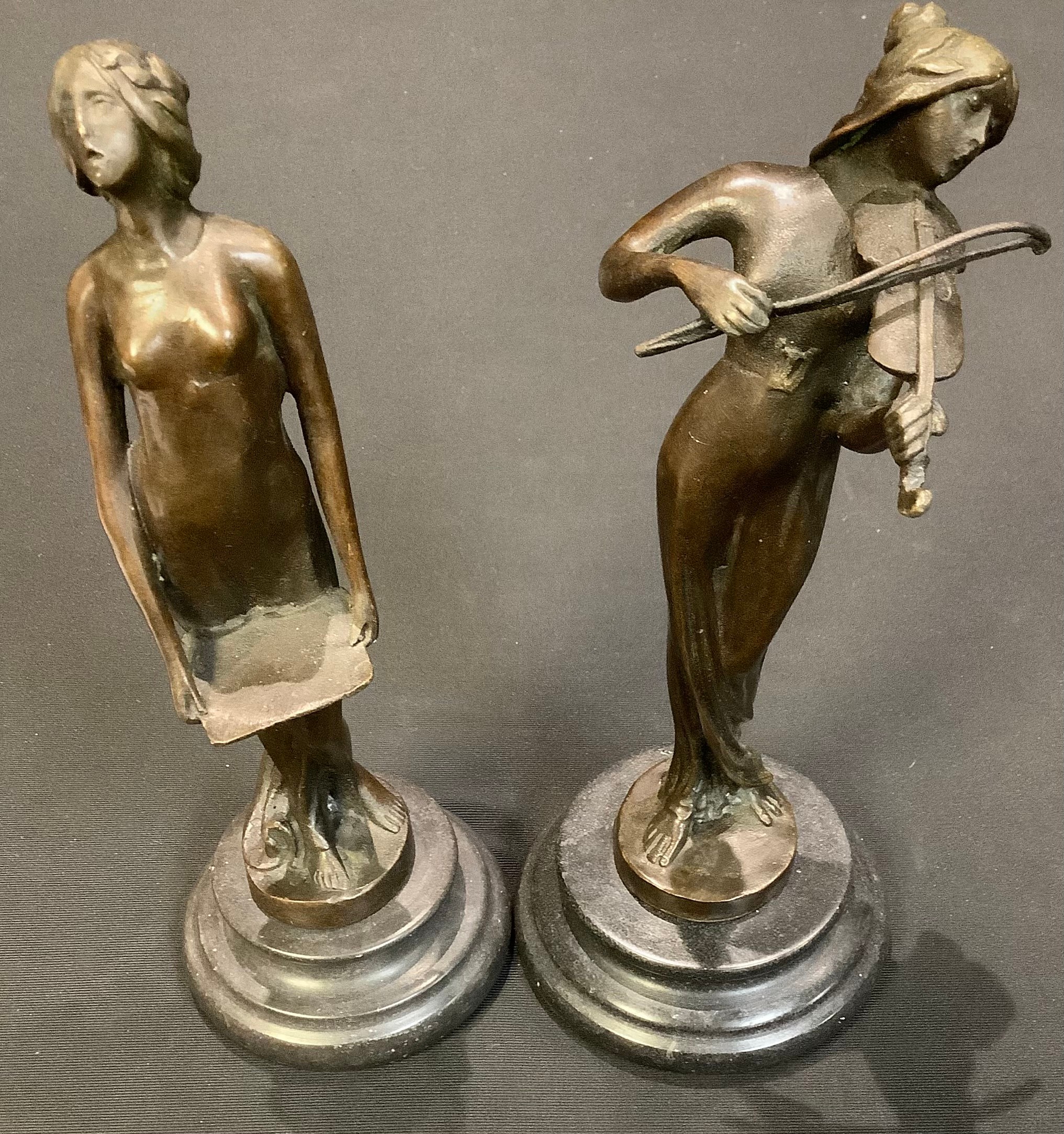 A dark patinated bronze figure, of a lady playing a violin; another of a lady holding a tray, each