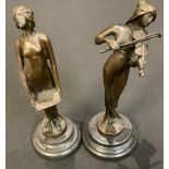 A dark patinated bronze figure, of a lady playing a violin; another of a lady holding a tray, each