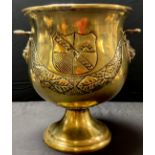 An 19th century French brass pedestal wine cooler, hammered decoration of swags and crests, lion