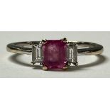 An 18ct white gold and pink sapphire ring, the central emerald cut stone flanked by two emerald