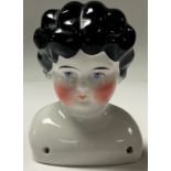 A late 19th century porcelain doll's head and shoulders, moulded painted black hair, blue eyes, rosy