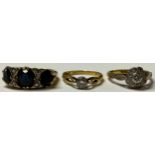 An 18ct gold graduated three stone sapphire ring, the platinum bezel accented with four diamond