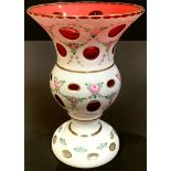 A Bohemian flashed glass pedestal vase, painted with flowers, 21cm high