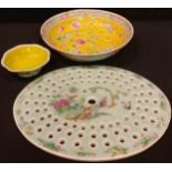 A Chinese Cantonese oval strainer plate, painted in colours with lotus and birds on a celedon