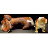 A painted cast iron model of a bulldog, 22cm long; a leatherette doorstop modelled as a dog (2)
