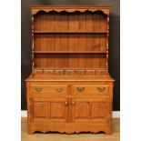 An oak dresser, moulded cornice above a pair of plate racks and seven small drawers, the