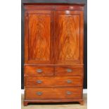 A 19th century mahogany linen press, outswept cornice above a pair of panel doors enclosing three