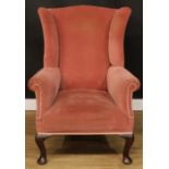 A George II Revival wingback armchair, stuffed-over upholstery, scroll arms, cabriole forelegs,