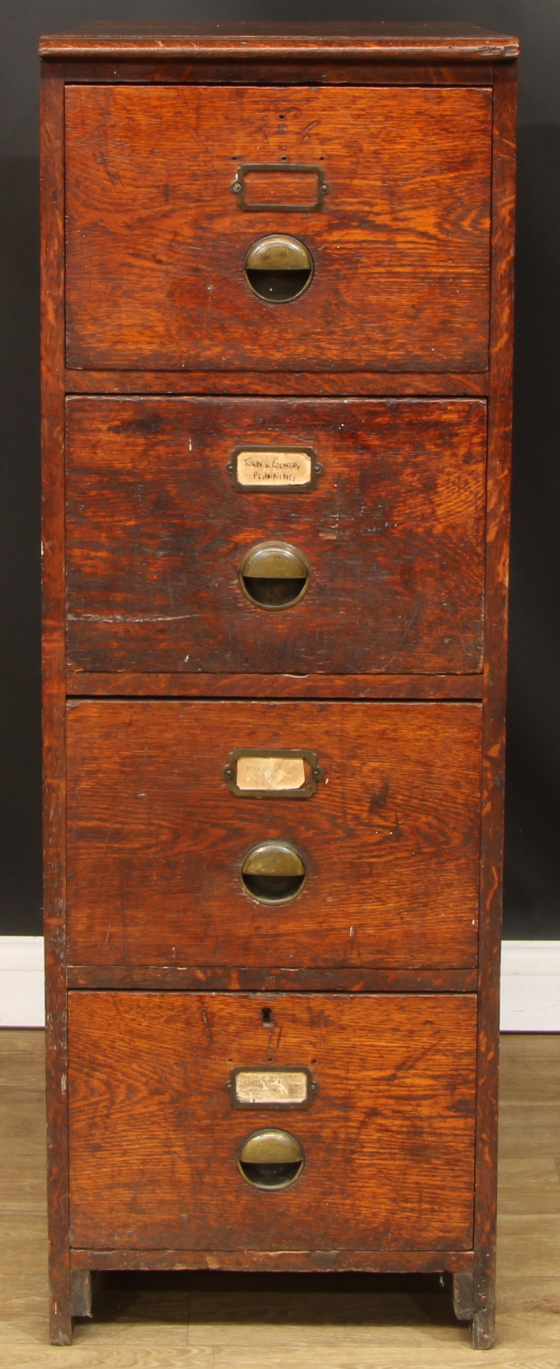 An early 20th century oak filing chest, of four drawers, brass cup handles, 130cm high, 45cm wide,