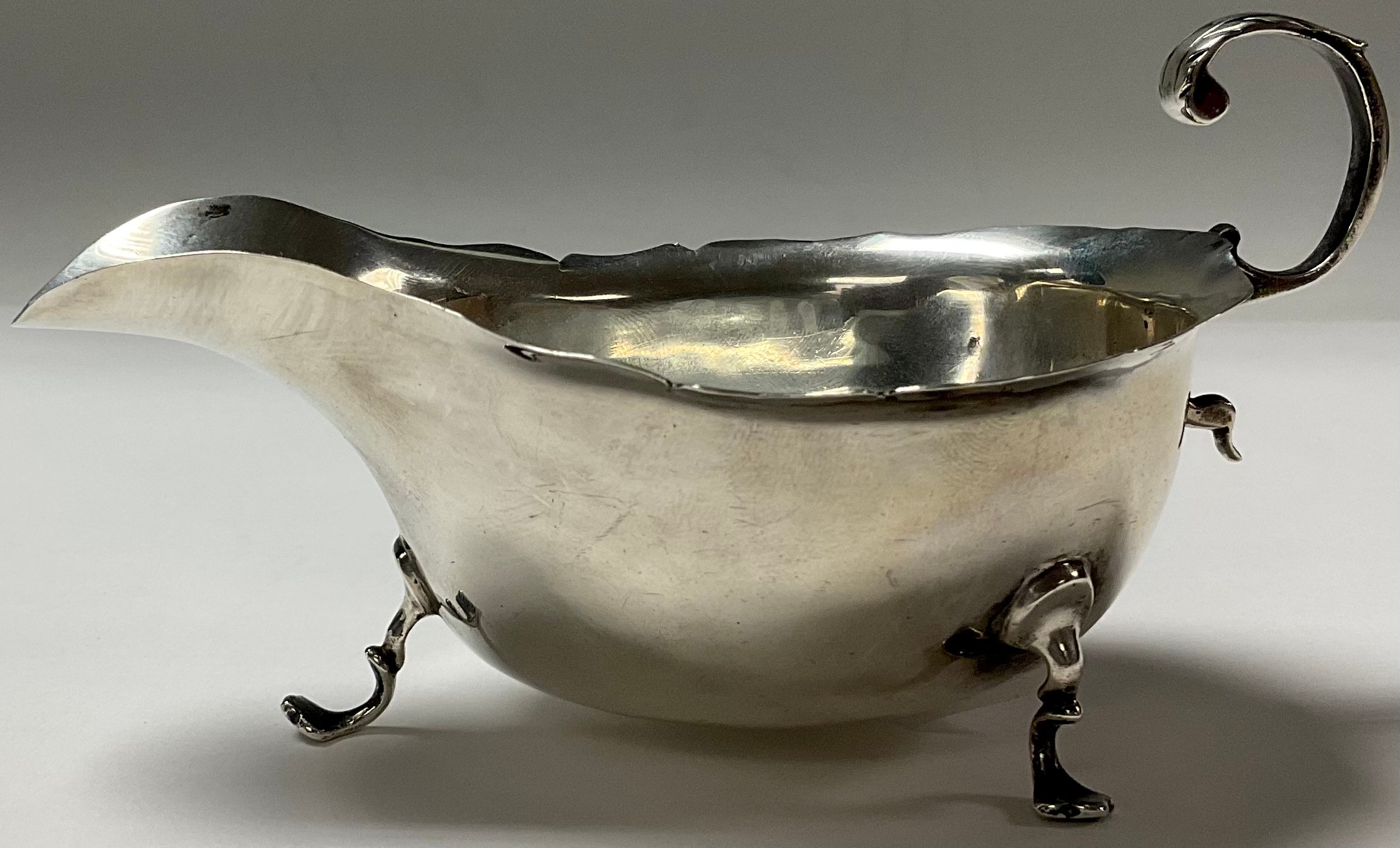 An Edwardian silver sauce boat in George III style, acanthus capped flying s-scroll handle,