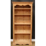 A pine open bookcase, moulded cornice above four adjustable shelves, flanked by fluted stiles,