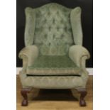 A George II style wingback armchair, stuffed-over upholstery, scroll arms, squab cushion, cabriole