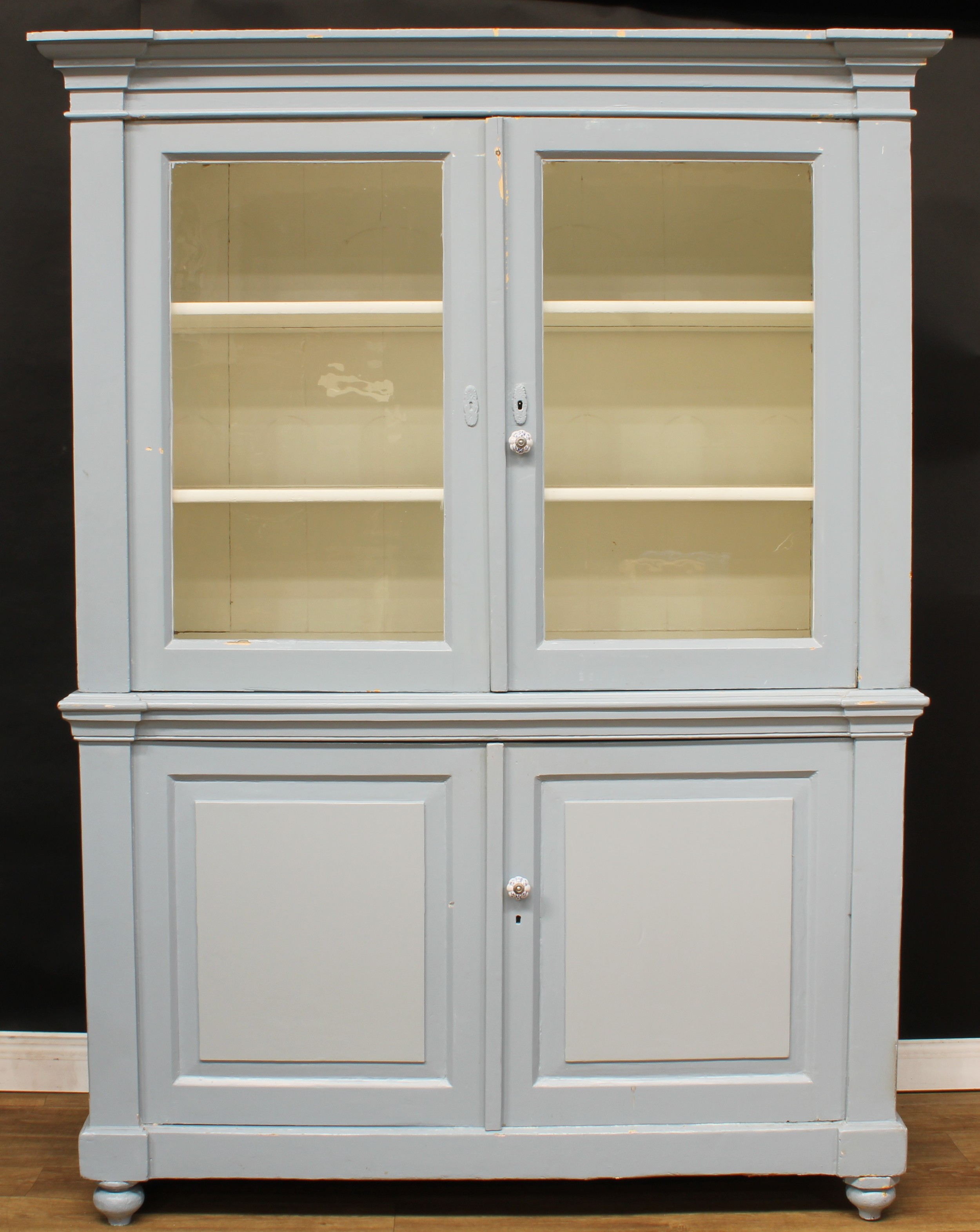 A Victorian painted pine housekeeper’s cupboard, outswept cornice above a pair of glazed doors