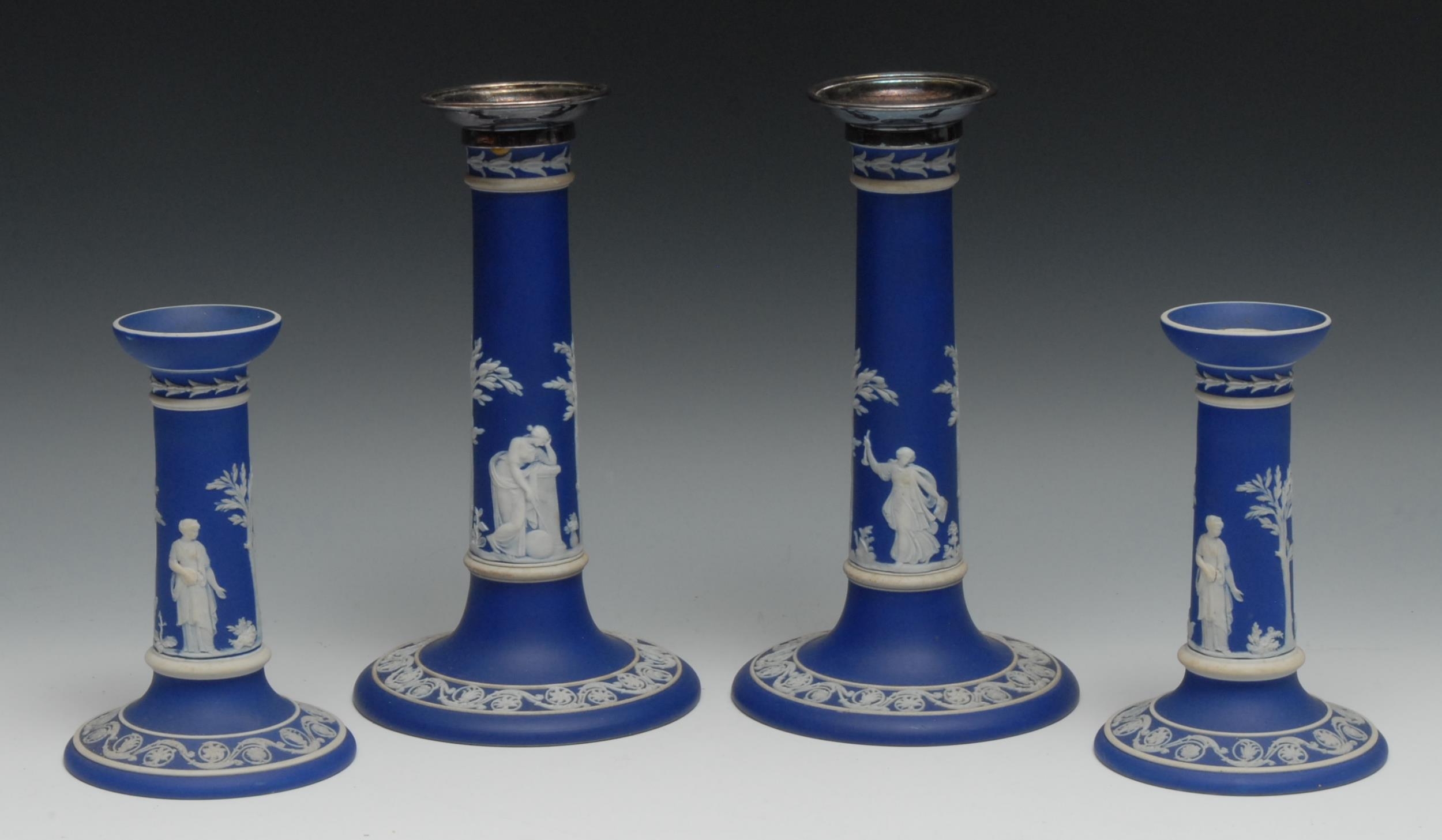 A pair of Wedgwood Jasperware candlesticks, plated drip pans, typically sprigged in white with