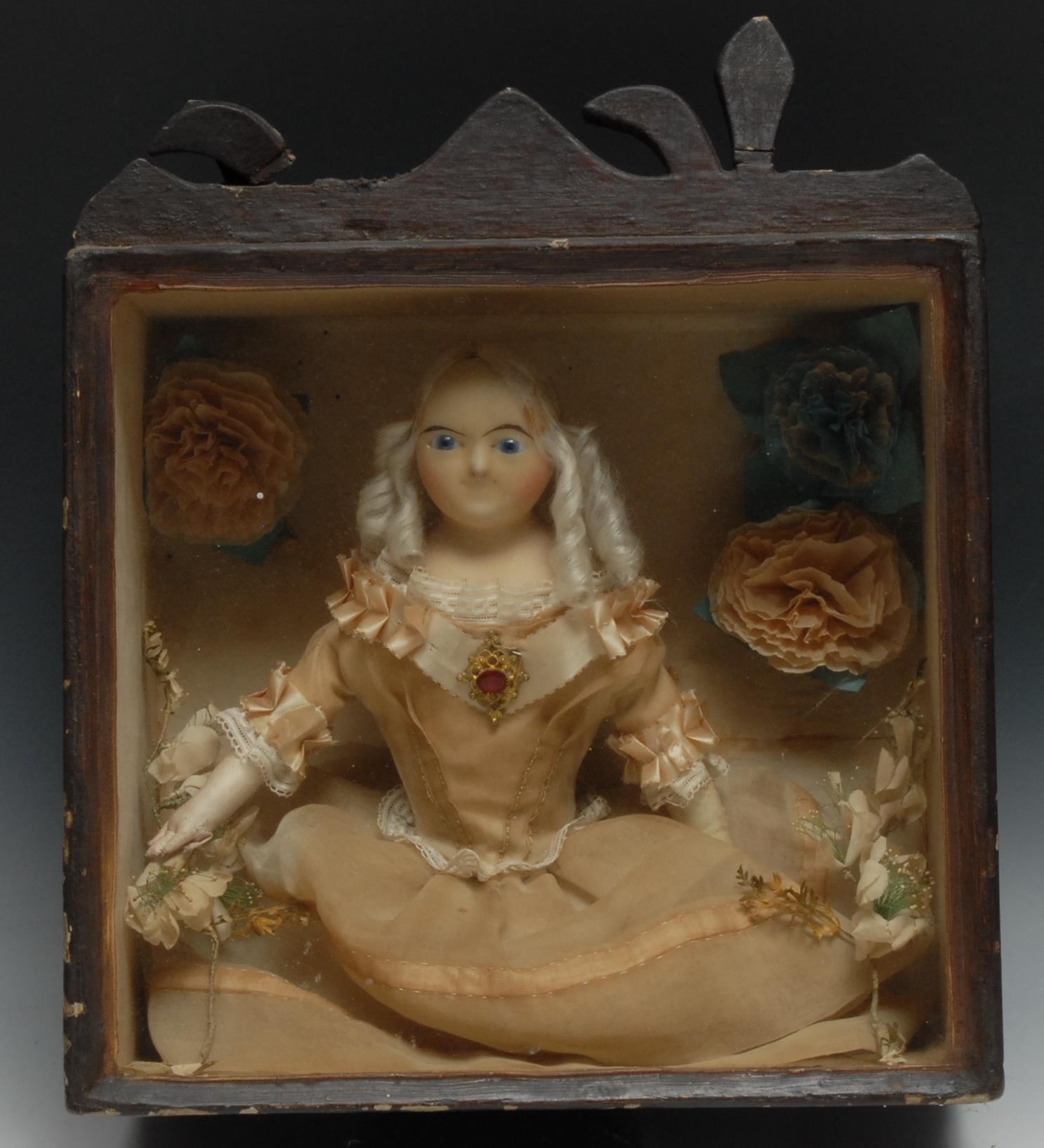 A 19th century wax doll diorama, finely dressed and set amongst flowers, stained pine case, 38cm