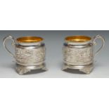 A pair of Victorian silver wine mugs, each chased with Bacchic masks and vine, beaded borders,