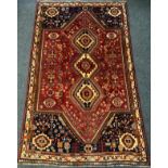 A Persian Qashgai rug / carpet, triple medallion centre within a field woven with stylised flowers