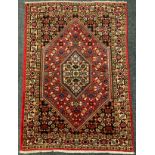 A Bidjar rug / carpet, intricately woven with stylised floral motifs in shades of red, indigo and