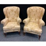 A pair of wingback armchairs, upholstered in a cream textured floral and box patterned fabric,