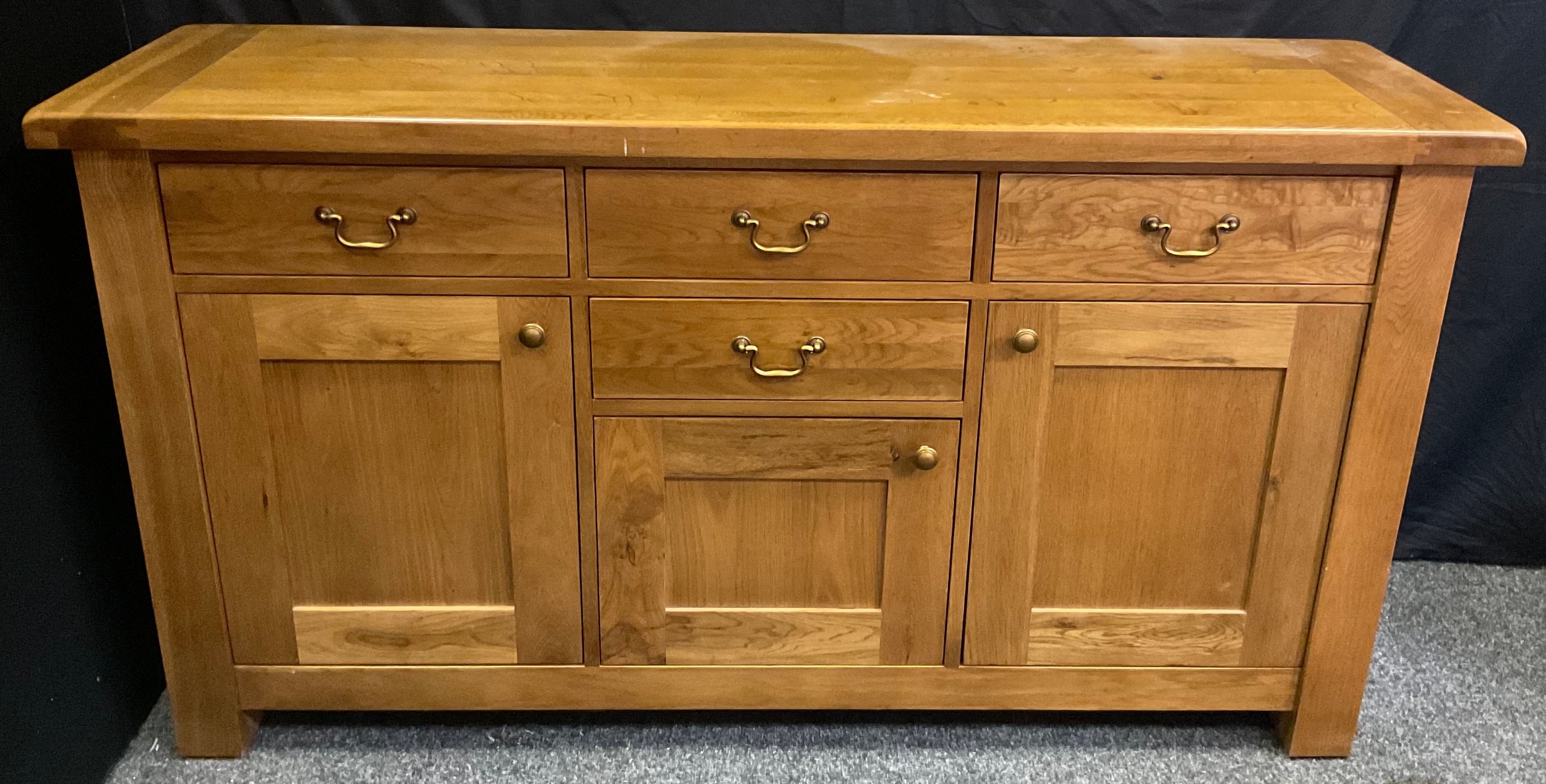 A Contemporary light oak sideboard, having an arrangement of four drawers and three cupboard