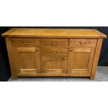 A Contemporary light oak sideboard, having an arrangement of four drawers and three cupboard