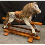 A 20th century painted dapple grey rocking horse (lacking its support / swing brackets), 95cm tall x