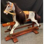 A 20th century painted dapple-grey rocking horse (lacking its support / swing brackets), 97cm tall x