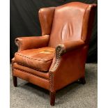 A Bendic International wing back armchair, tan leather, 102cm tall x 78cm wide x 73cm deep.