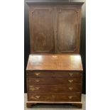 A George III mahogany bureau bookcase, the moulded cornice above two panelled doors, the base with