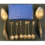 A set of six silver coloured metal tea spoons, the tops terminating with rickshaws, kettle, house