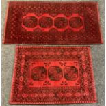 An Afghan style woollen rug, with three canted reserves in black on a red ground, 150cm x 106cm;