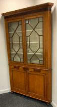 A George III oak floor standing corner cabinet, moulded cornice above two astragal glazed doors, the