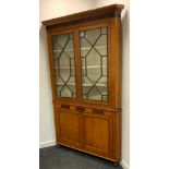 A George III oak floor standing corner cabinet, moulded cornice above two astragal glazed doors, the
