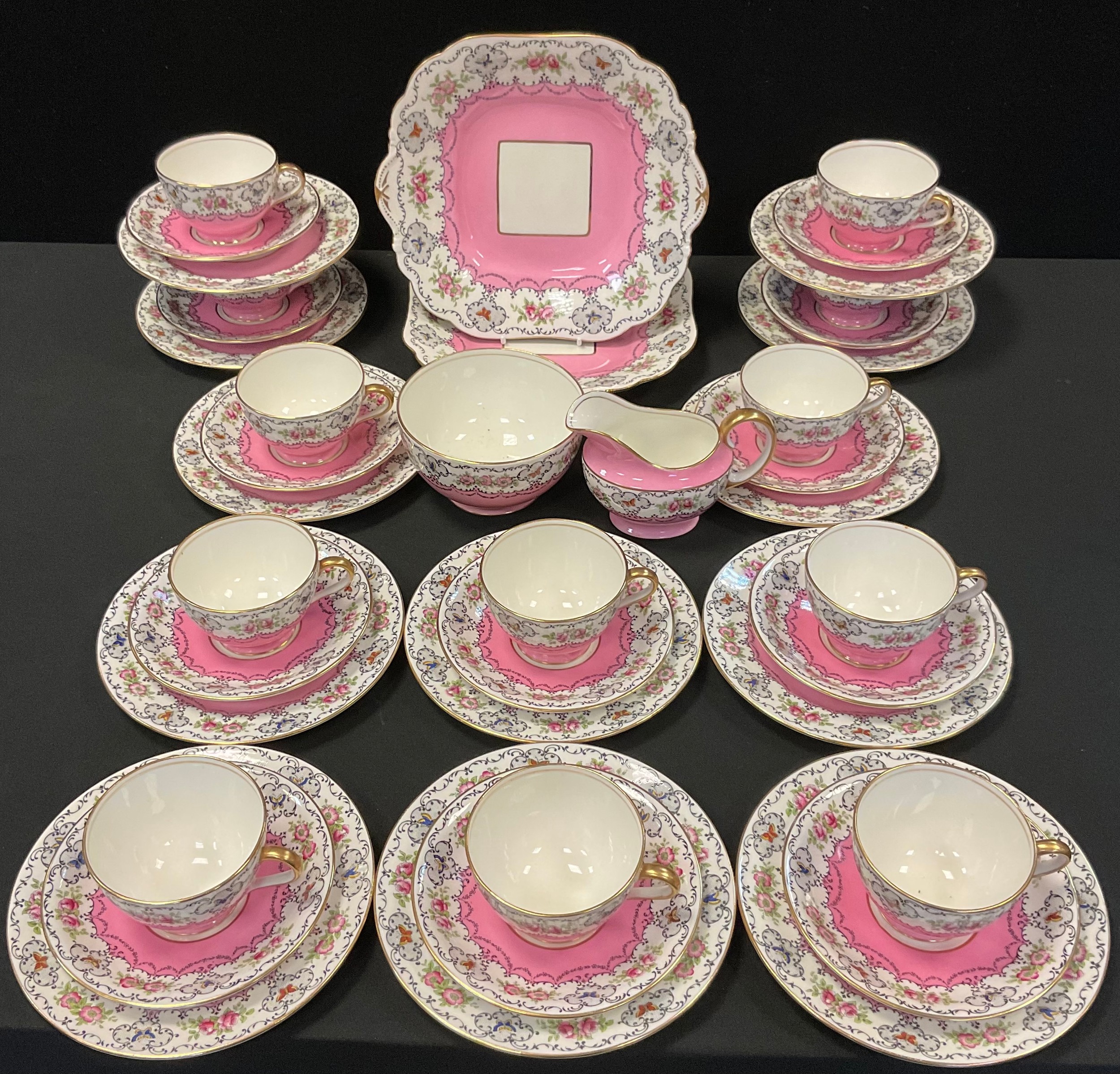 An Aynsley teaset, for twelve, decorated with a band of pink roses, flowers and butterflies