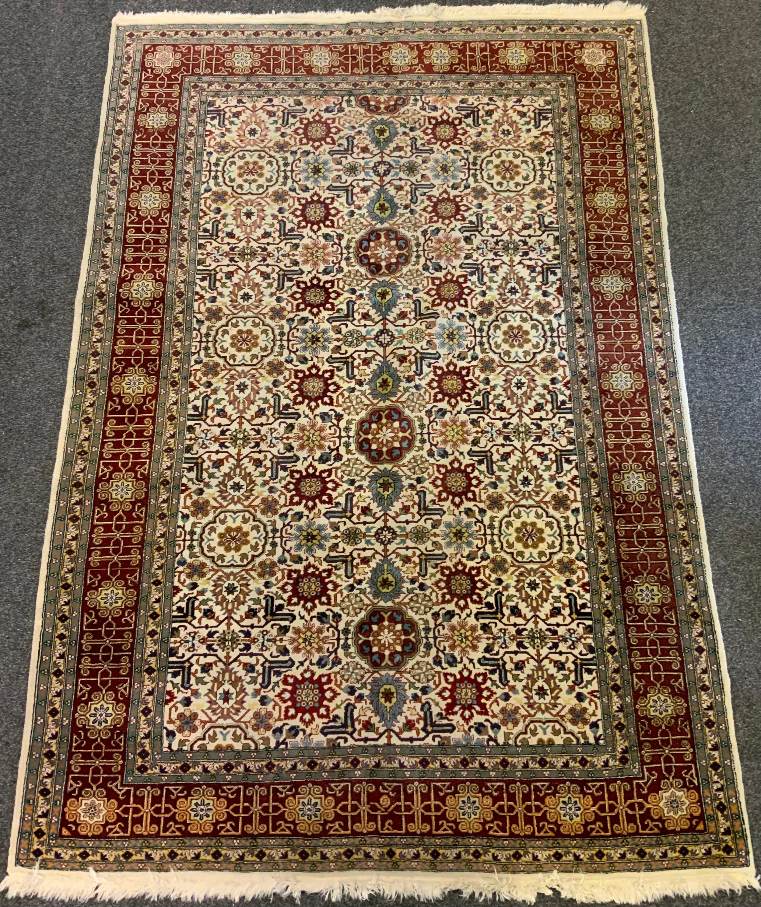 A Caucasian hand-made rug, large central field with stylised floral motifs in shades of red,