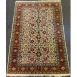 A Caucasian hand-made rug, large central field with stylised floral motifs in shades of red,