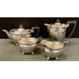 A George VI silver matched four piece tea set, teapot, hot water jug, sugar bowl and milk jug, ebony