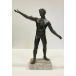 A bronzed spelter figure, 'Male Gymnast standing with arms extended', mounted on a white marble