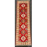 A Kazak small runner carpet / rug, multiple medallions within a field of light red, enclosed