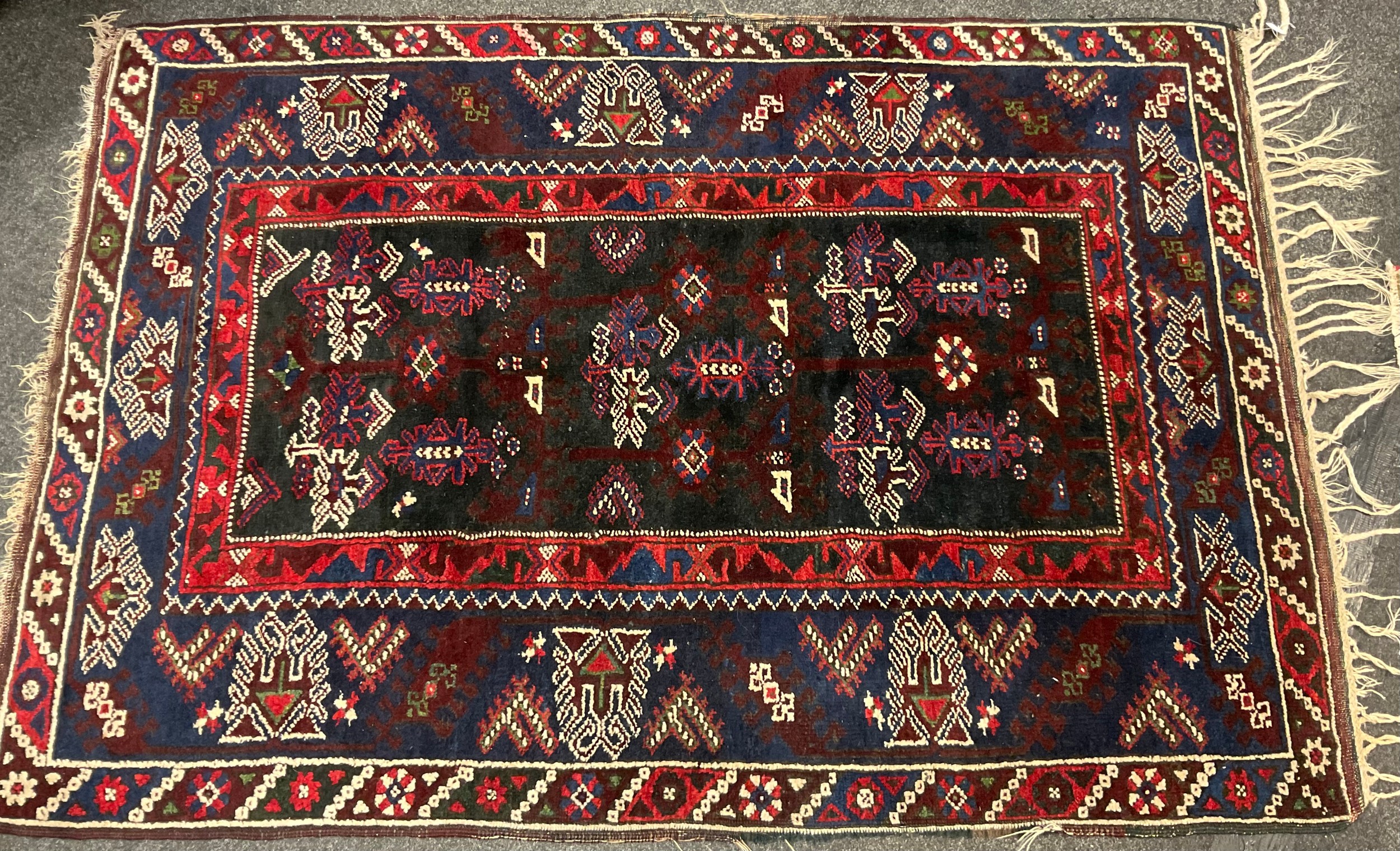 A Persian/Turkish hand knotted rug, central rectangular panel of geometric motifs, within four