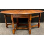 A Nigel Griffiths style large oak gate leg dining / kitchen table, oval top when leaves extended,