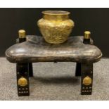 An early 20th century camel saddle stool, black leather seat cushion; a Middle Eastern hammered