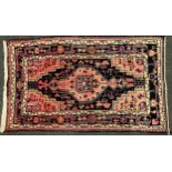 A Persian/Turkish rug, central geometric panel within stepped surround, in tones of pink, black,