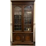 An early 20th century ‘Arts and Crafts’ style bookcase cabinet, moulded cornice, pair of glazed