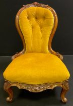 A Victorian upholstered walnut nursing chair, shaped button back with carved cresting, carved side