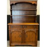 A mid 20th century oak dresser, plate rack top, above two short drawers, and pair of cupboard doors,