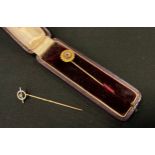 A 15ct gold ruby tie pin, floral top, stamped .625, spiral shaft, 1.2g gross; another unmarked