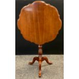 A 20th century reproduction mahogany tilt-top table, circular top with pie-crust edge, turned
