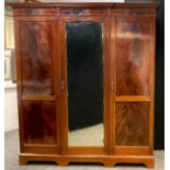 An Edwardian inlaid mahogany triple wardrobe, stepped pediment, central mirrored door, part fitted
